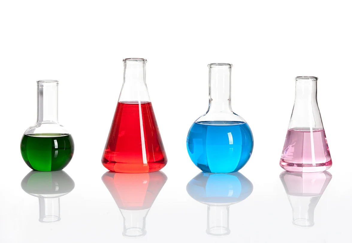 Line of 4 beakers with different colored liquids on a white background.