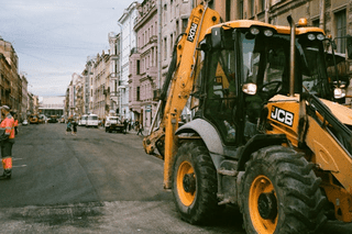 Construction backhoe loader parked in front of buildings.