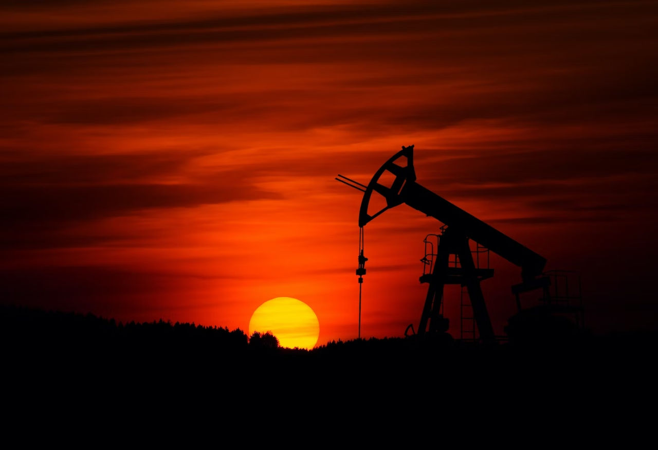 An oil well with a red sunset in the background.